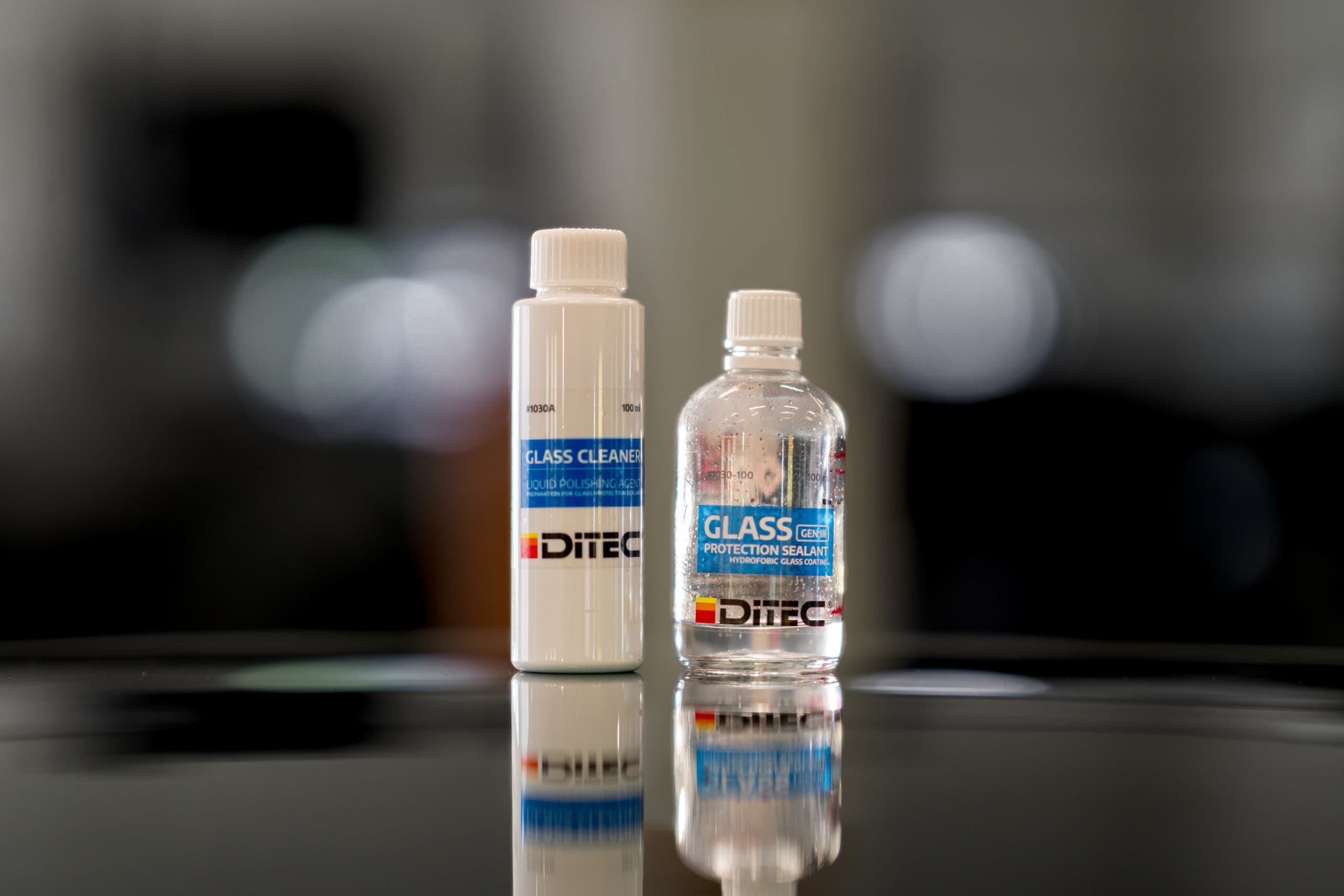 Ditec Glass Cleaner and Glass Protection Sealant bottles on a polished car surface